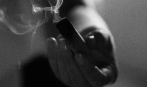 Hand holding a smoking incense stick.