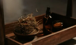 Wooden tray with dried herbs, a spray bottle, and a candle.