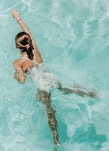 Woman in swimsuit floating peacefully in pool.
